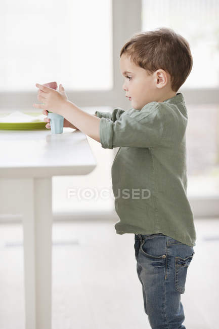 Мальчик играет с игрушками на столе дома — стоковое фото