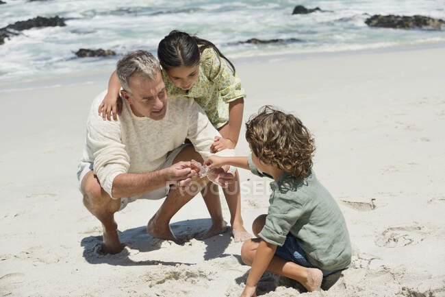 Діти з дідом на пляжі — стокове фото