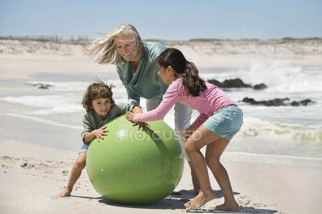 Жінка грає зі своїми онуками на пляжі — стокове фото