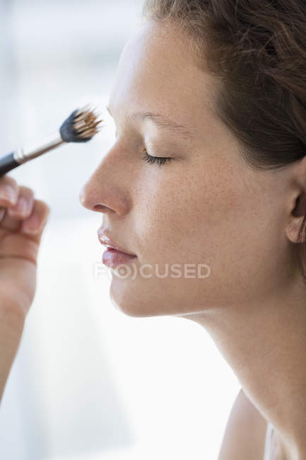 Close-up de jovem mulher escovando sobrancelha — Fotografia de Stock