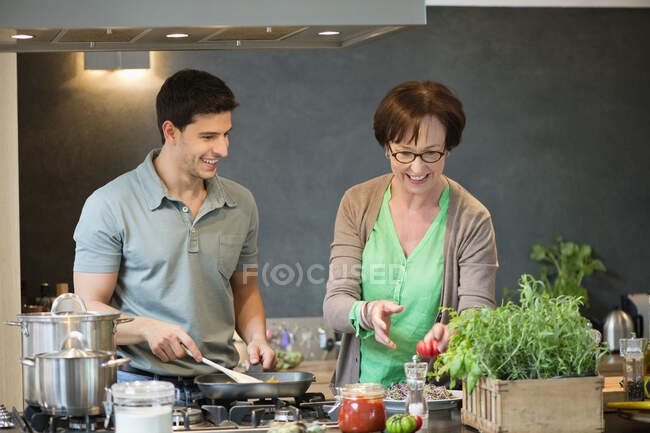 Жінка допомагає синові готувати їжу на кухні — стокове фото