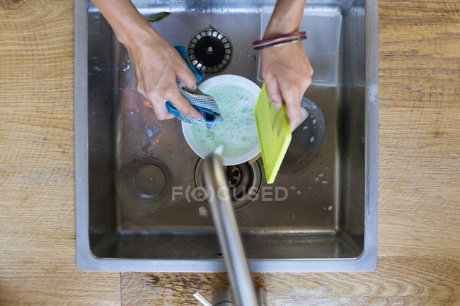 Close-up de mãos femininas lavar pratos na pia — Fotografia de Stock