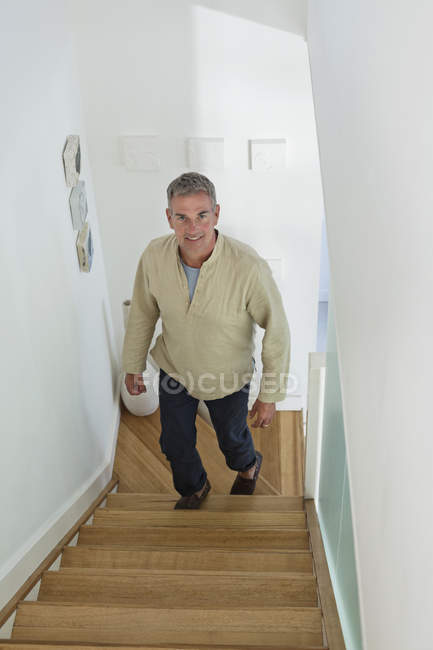 Mann geht zu Hause die Treppe hinauf und schaut in Kamera — Stockfoto