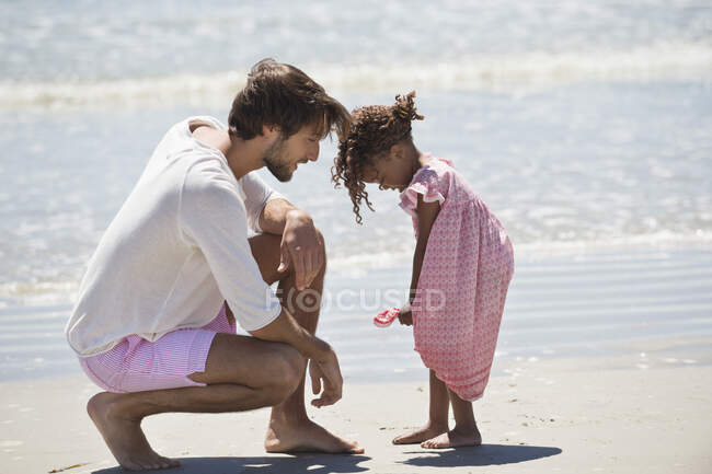 Hombre jugando con su hija la playa - foto de stock