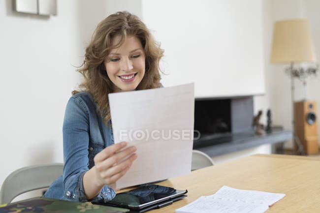 Femme trier les factures à la table en bois dans un appartement moderne — Photo de stock