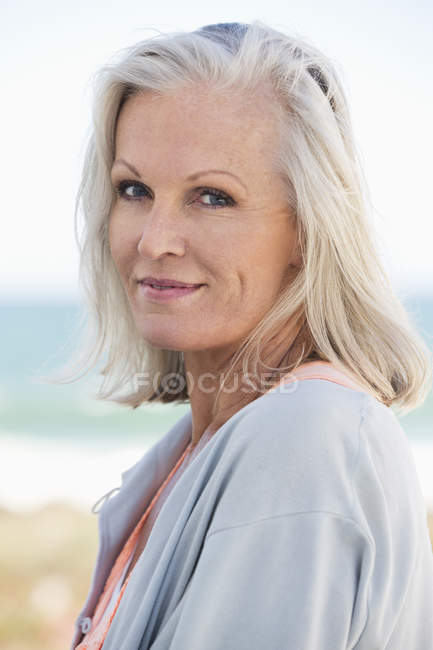 Retrato de una mujer mayor sonriente en la playa - foto de stock