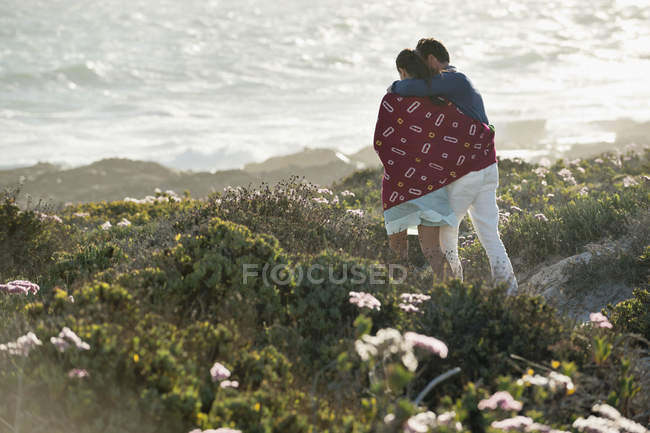 Abraçando casal andando na costa ensolarada — Fotografia de Stock