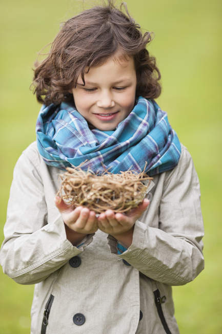 Portrait d'un garçon souriant tenant un nid d'oiseaux à l'extérieur — Photo de stock