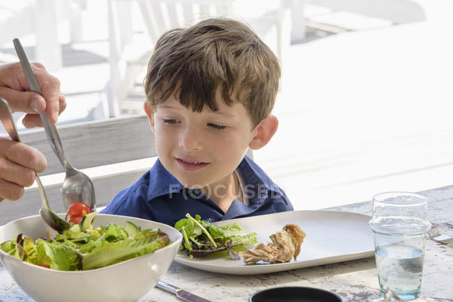Niño feliz comiendo en la mesa - foto de stock