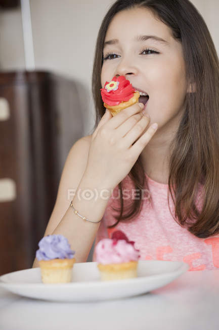 Menina feliz comer cupcake doce — Fotografia de Stock