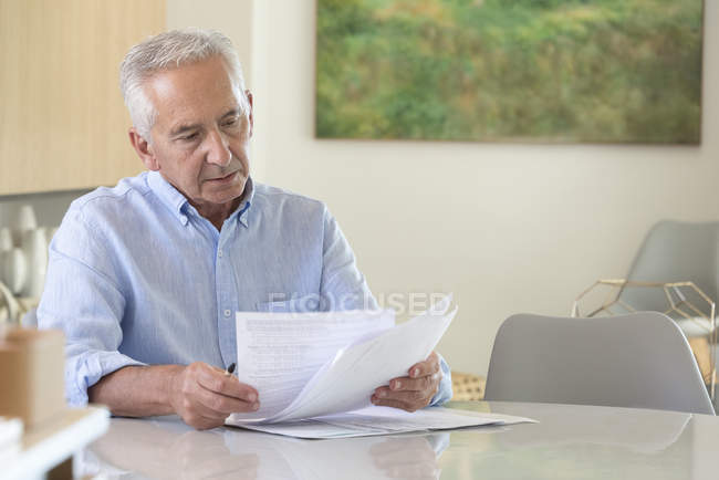 Focused senior man doing paperwork at home — Stock Photo