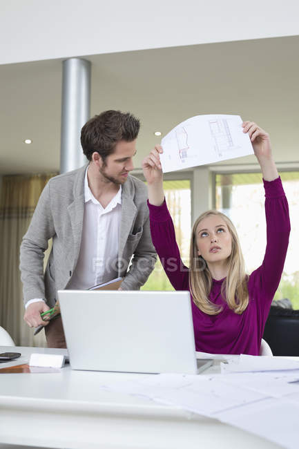 Woman examining architectural design in office with colleague — Stock Photo