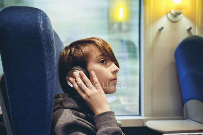 Хлопчик слухає музику з навушниками в громадському транспорті — стокове фото