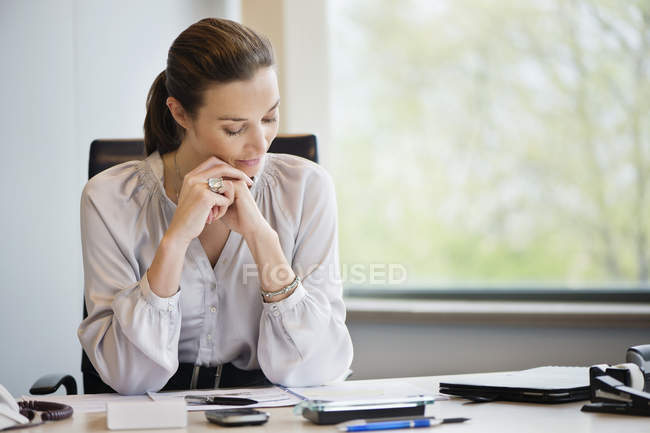 Businesswoman reading documents at desk in office — Stock Photo