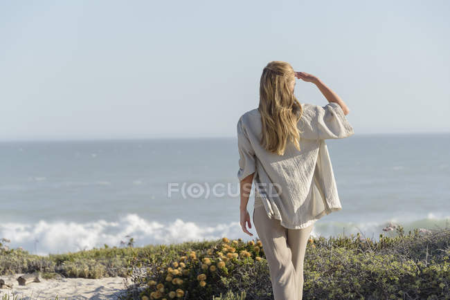 Visão traseira da mulher em pé na praia e olhando para a vista — Fotografia de Stock