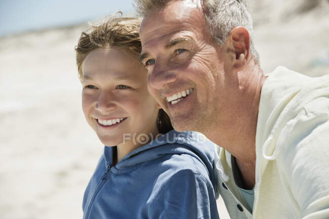 Чоловік посміхається зі своїм онуком на пляжі — стокове фото