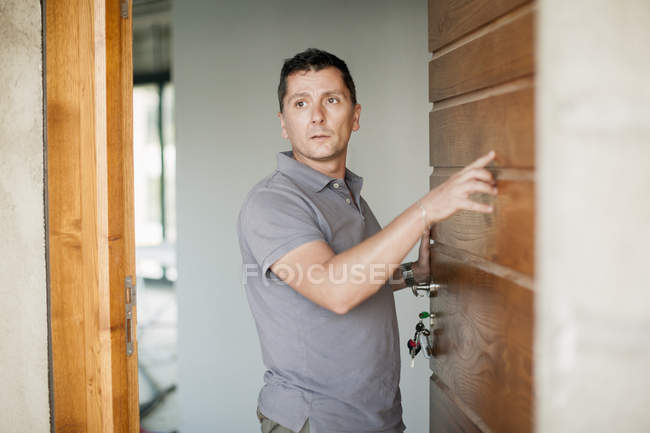 Чоловік стоїть біля дерев'яного дверного отвору і дивиться в сторону — стокове фото