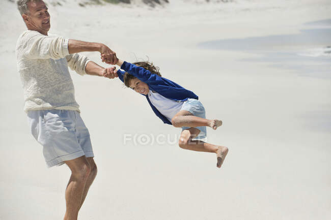 Mann spielt mit seinem Enkel am Strand — Stockfoto