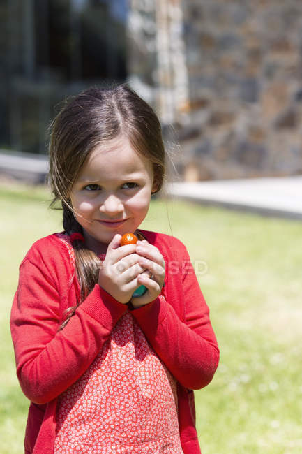 Крупный план улыбающейся маленькой девочки, держащей пасхальные яйца на газоне — стоковое фото