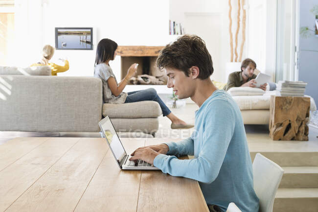 Homme utilisant un ordinateur portable avec ses amis utilisant des gadgets électroniques en arrière-plan — Photo de stock