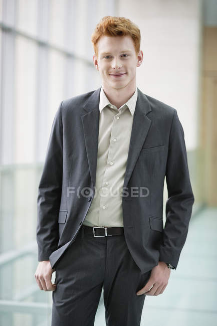 Retrato de jovem empresário sorridente em pé sobre fundo embaçado — Fotografia de Stock