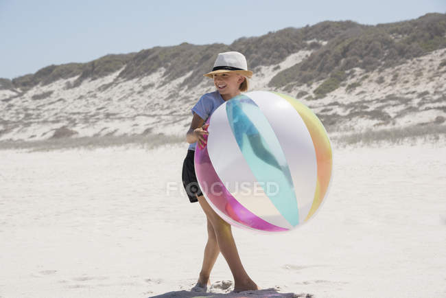 Счастливая маленькая девочка, играющая на пляже с цветным мячом — стоковое фото