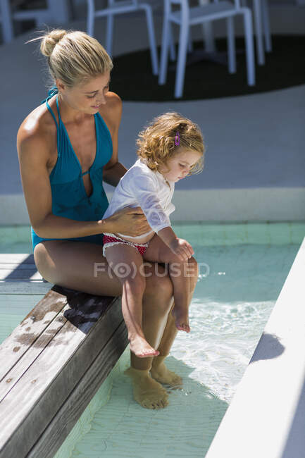 Belas sessões de mulher à beira da piscina com sua filha bebê — Fotografia de Stock