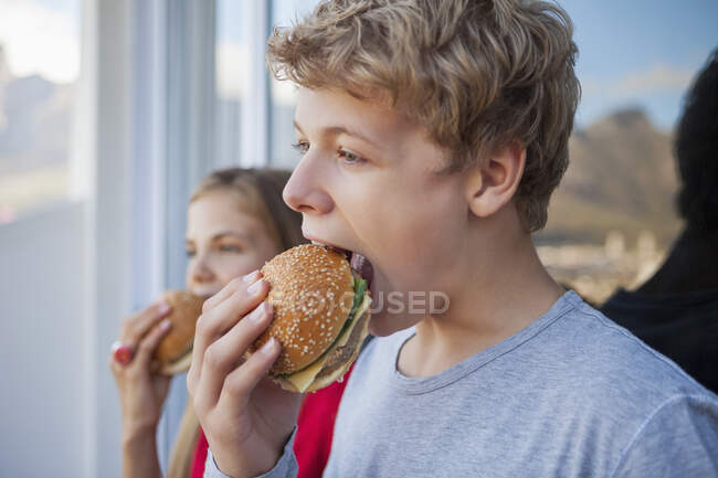 Primer plano de dos amigos comiendo hamburguesa - foto de stock