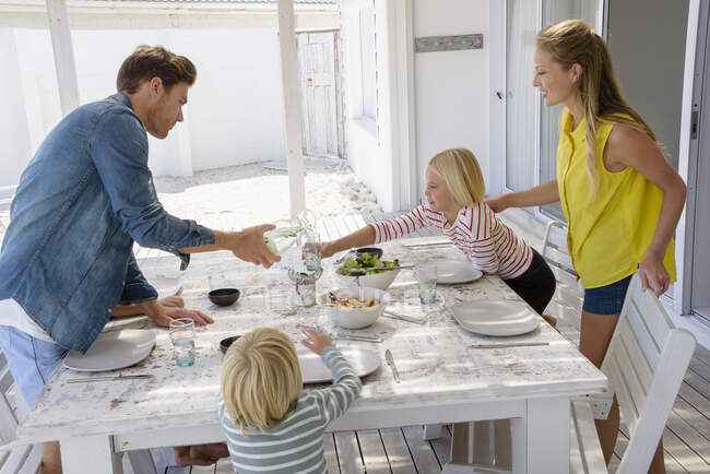 Família jovem desfrutando de comida no alpendre — Fotografia de Stock
