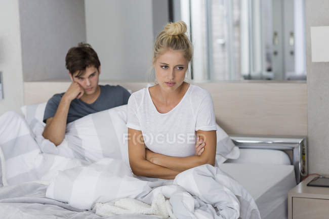 Jeune couple assis sur le lit avec des difficultés relationnelles — Photo de stock