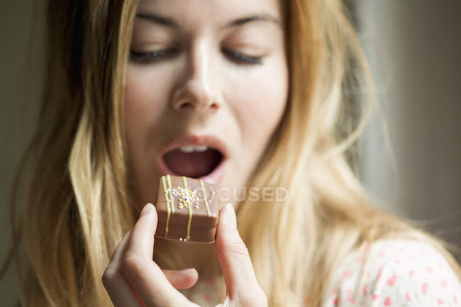 Close-up de mulher loira comendo chocolate doce — Fotografia de Stock
