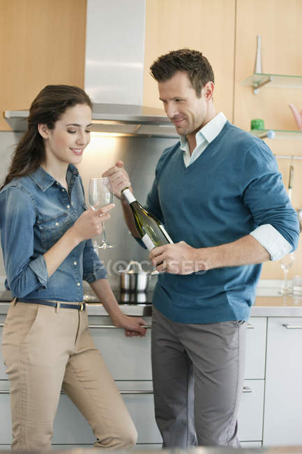 Sonriente pareja bebiendo vino en la cocina - foto de stock