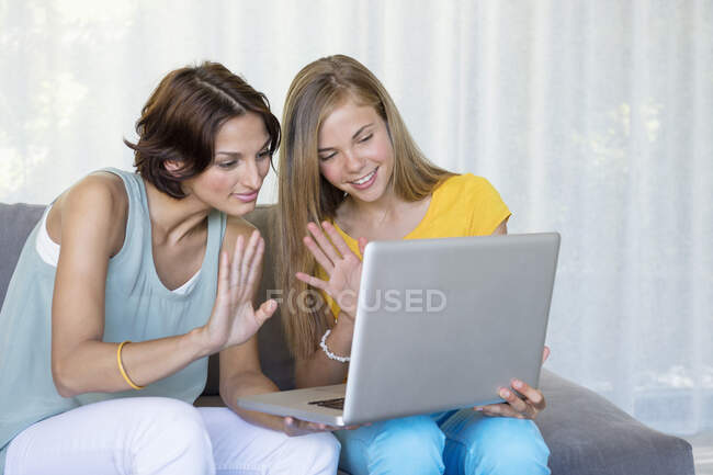 Madre e hija charlando en un portátil - foto de stock