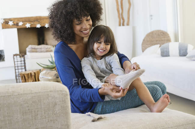 Mulher vestindo meias para sua filha e sorrindo — Fotografia de Stock