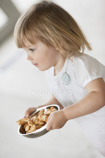 Primer plano de linda niña llevando un tazón de comida - foto de stock