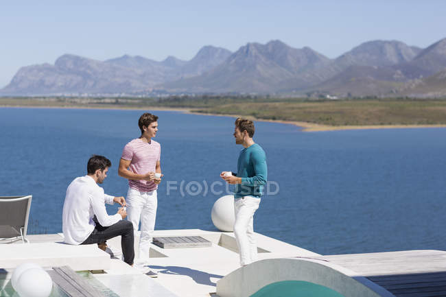 Smiling men drinking coffee and relaxing at resort — Stock Photo