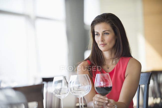 Жінка тримає келих і думає в ресторані — стокове фото