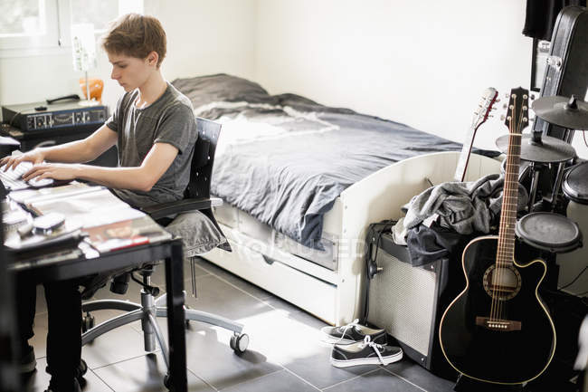 Мальчик-подросток, печатающий дома на ноутбуке — стоковое фото
