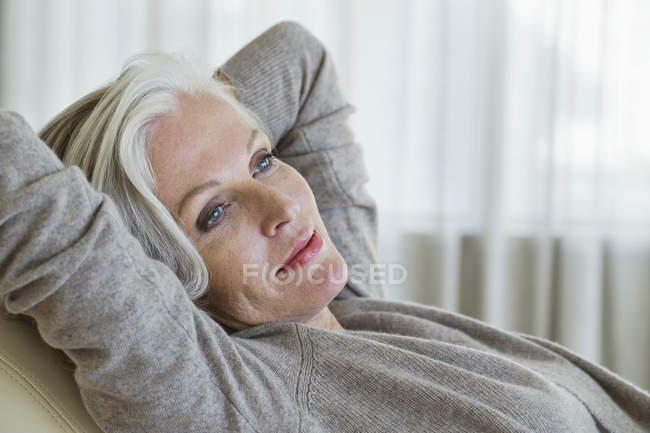 Расслабленная пожилая женщина, лежащая на стуле дома — стоковое фото