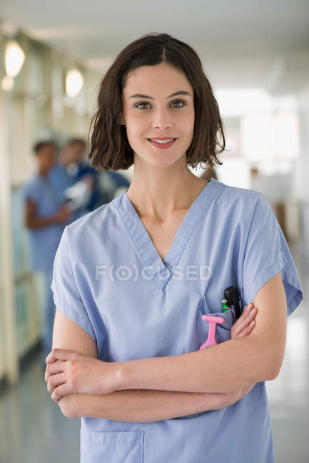 Портрет усміхнене жіночий медсестра стоячи з обіймами перетнула — стокове фото
