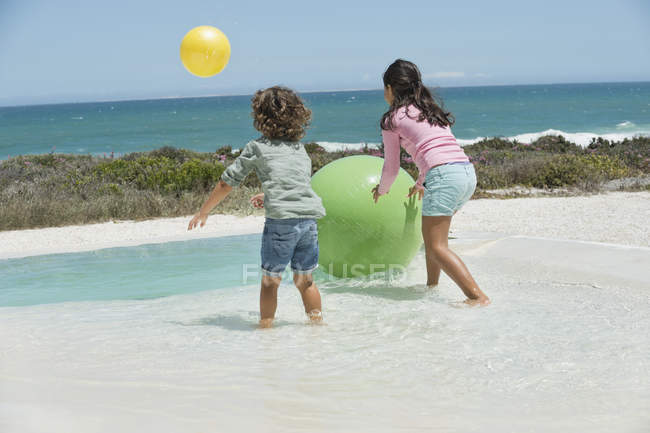 Веселі діти грають на піщаному пляжі з кульками — стокове фото