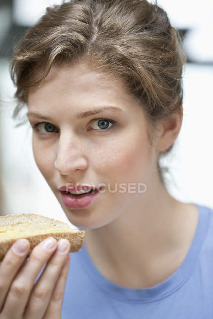 Portrait of woman holding slice of bread and staring at camera — Stock Photo