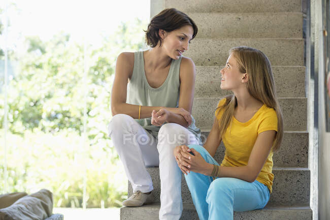 Мати і дочка сидять на сходах і розмовляють один з одним — стокове фото