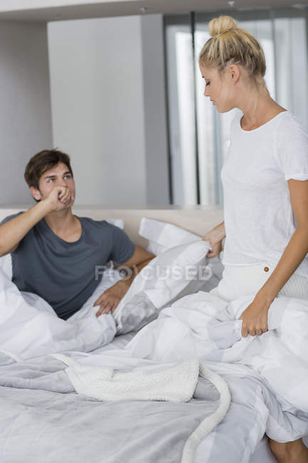 Joven pareja seria sentada en la cama y hablando - foto de stock