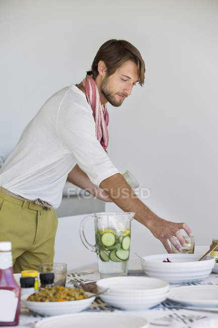 Joven hombre arreglando mesa de comedor - foto de stock