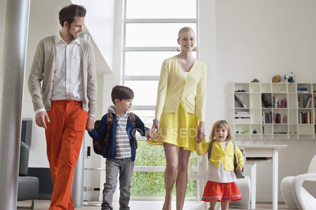 Щаслива пара з маленькими дітьми, що стоять в сучасній квартирі — стокове фото