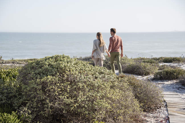 Щаслива пара ходити в рослинність на узбережжі моря — стокове фото