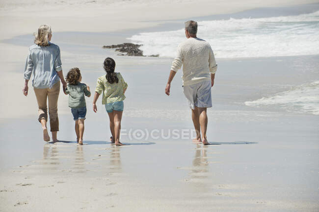 Crianças caminhando com seus avós na praia — Fotografia de Stock