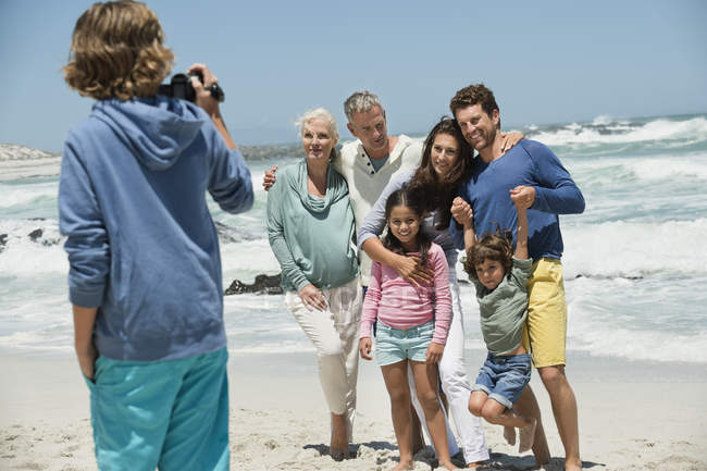 Ragazzo scattare foto di famiglia in posa sulla spiaggia di sabbia — Foto stock