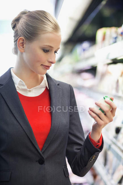 Молода бізнес-леді купує їжу в супермаркеті — стокове фото